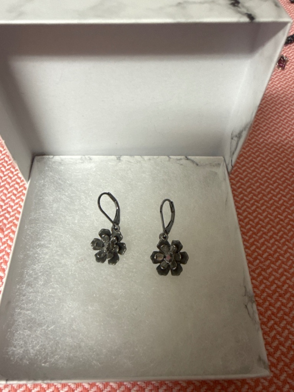 Grey silver toned floral earrings with black gem in middle